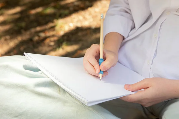 Anonymous girl making notes in the blank paper album.