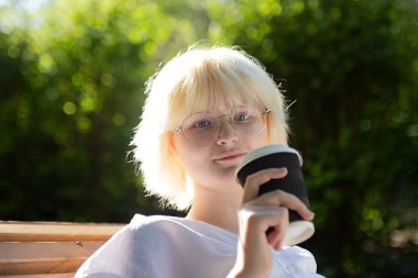 Sarışın genç kız dışarıdaki el işi kağıt bardaktan kahve içtiğini duymuş..