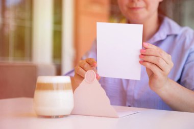 Closeup photography of anonymous woman,holding blank certificate gift certificate gift outside.Sunlight on background.
