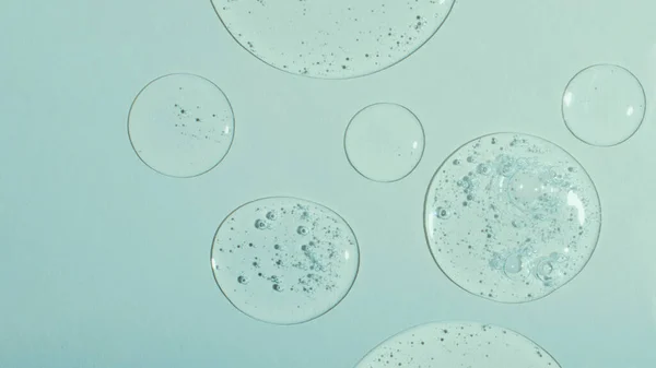 Top view of liquid cosmetics gel with bubbly structure on pastel cyan background,large banner.