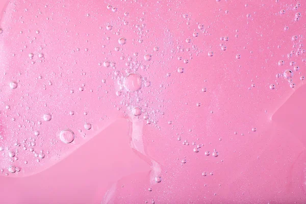 Macro photography of bubbly smear on raspberry pink background.