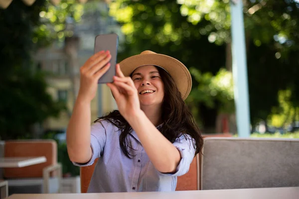 Smiling millennial woman making selfie outside.