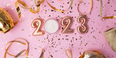 Pembe arka plandaki kozmetik konteynırlarının üst görüntüsü. Üzerinde 2023 numaralı gül ve altın rengi konfeti. Büyük pankart..