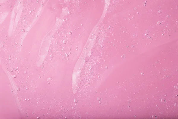 Macro photography of bubbly smear on raspberry pink background.