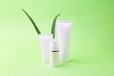 Arka planda aloe vera olan bir grup kozmetik konteynırı. Organik kozmetik konsepti..