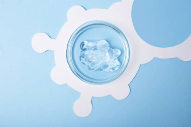 Üzerinde kozmetik jel örnekleri olan petri kabının üst görüntüsü. Etrafında beyaz molekül yapısı var..