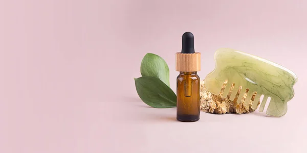 Eco friendly cosmetics oil dropper with hair brush near it,green leafs on background.Concept of hair care.Large banner with negative space.