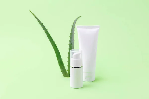 Blank cosmetics tube and dispenser with aloe vera on background.Organic cosmetic concept.