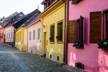 Romanya 'nın Transilvanya (Transilvanya) bölgesindeki Sighisoara kalesinin tarihi merkezinde güneşli bir yaz gününde eski renkli boyalı evler
