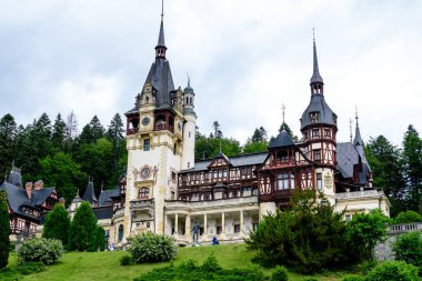 Romanya 'nın Sinaia kentinde bulutlu bir yaz gününde Bucegi Dağları (Muntii Bucegi) yakınlarındaki Peles Kalesi' nin (Castelul Peles) güzel neo-rönesans binası