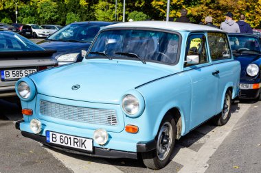 Bükreş, Romanya, 24 Ekim 2021: Canlı mavi bir Trabant Alman klasik arabası güneşli bir sonbahar gününde şehir merkezindeki bir caddeye park etti