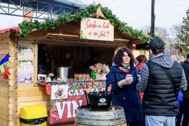 Bükreş, Romanya - 28 Kasım 2021: Güneşli bir günde, Drumul Taberei Park 'taki (Parcul Drumul Taberei) Noel Pazarı' nda geleneksel içki, yiyecek ve tatlıların keyfini çıkaran insanlar
