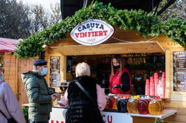 Bükreş, Romanya - 28 Kasım 2021: Güneşli bir günde, Drumul Taberei Park 'taki (Parcul Drumul Taberei) Noel Pazarı' nda geleneksel içki, yiyecek ve tatlıların keyfini çıkaran insanlar