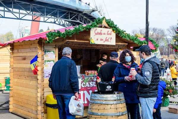 Bükreş, Romanya - 28 Kasım 2021: Güneşli bir günde, Drumul Taberei Park 'taki (Parcul Drumul Taberei) Noel Pazarı' nda geleneksel içki, yiyecek ve tatlıların keyfini çıkaran insanlar