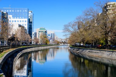 Bucharest, Romania, 20 November 2021: Modern buildings and offices near Dambovita river and cloudy blue sky in the center of the city, in a sunny autumn day