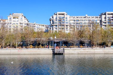 Bucharest, Romania, 20 November 2021: Modern buildings and offices near Dambovita river and cloudy blue sky in the center of the city, in a sunny autumn day