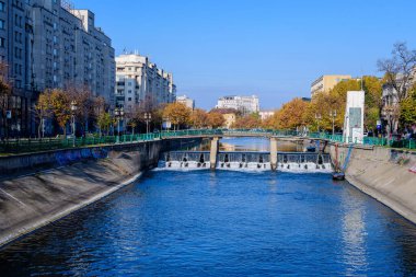 Bükreş, Romanya, 22 Kasım 2020: Romanya 'nın başkenti Bükreş' te güneşli bir sonbahar gününde Dambovita nehri, eski binalar ve sarı, turuncu ve kahverengi yapraklı manzara