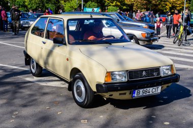 Bucharest, Romania, 24 October 2021: One vivid yellow Citroen French vintage car in traffic in a street at an event for vintage cars collections, in a sunny autumn day