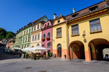 Sighisoara, Romania, 13 July 2021: Old colorful painted houses and restaurants in the historical center of the Sighisoara citadel, in Transylvania (Transilvania) region, in a sunny summer day