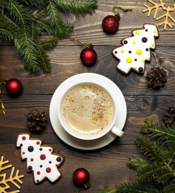 Lezzetli süt köpüklü bir fincan kahve ev yapımı zencefilli kek ve kahverengi ahşap bir masada Noel süslemeleri. Yeni yıl ve Noel konsepti. Noel kartı..