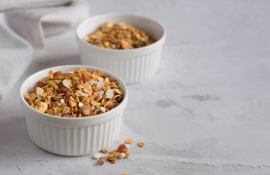 Işık masasında beyaz bir kase ev yapımı müsli. Sağlıklı bir kahvaltı için fındıklı ve kuru meyveli granola. Uzayı kopyala Seçici odak.