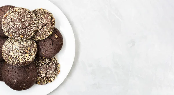 Ev yapımı çikolatalı kurabiyeler ve beyaz bir tabakta ceviz. Uzayı kopyala Üst Manzara. Yakın plan..