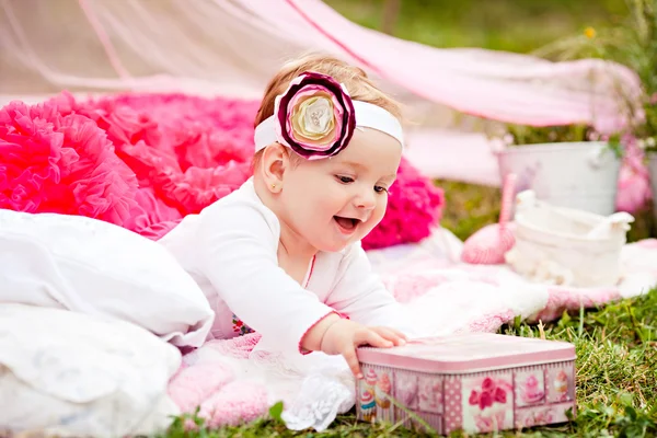 Cute newborn girl smiling on grass in pink skirt with flower — Stock Photo, Image