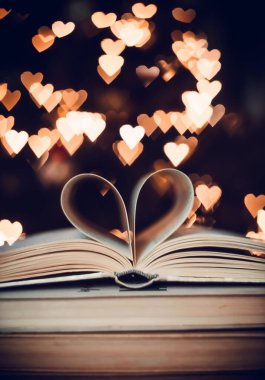 Bokeh kalplerinin arka planında kalp şeklinde bir kağıt kitap. Sevgililer Günü kavramı. Aşk sembolü. 