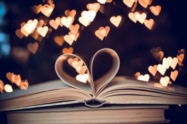 Bokeh kalplerinin arka planında kalp şeklinde bir kağıt kitap. Sevgililer Günü kavramı. Aşk sembolü. 