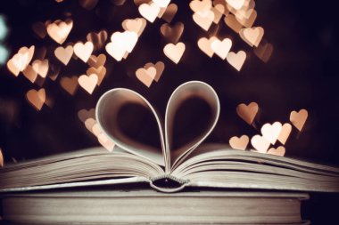 Bokeh kalplerinin arka planında kalp şeklinde bir kağıt kitap. Sevgililer Günü kavramı. Aşk sembolü. 