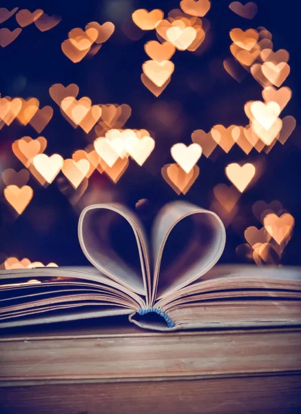 Bokeh kalplerinin arka planında kalp şeklinde bir kağıt kitap. Sevgililer Günü kavramı. Aşk sembolü. 