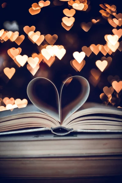Paper book in the shape of a heart on the background of bokeh hearts. valentine's day concept.love symbol