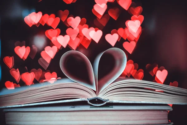 Bokeh kalplerinin arka planında kalp şeklinde bir kağıt kitap. Sevgililer Günü kavramı. Aşk sembolü. 