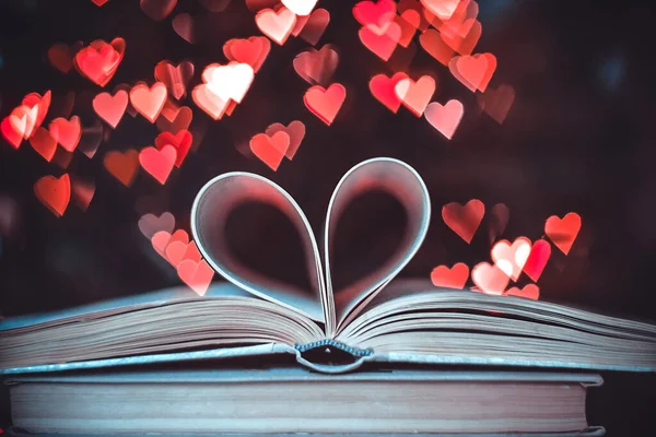 Bokeh kalplerinin arka planında kalp şeklinde bir kağıt kitap. Sevgililer Günü kavramı. Aşk sembolü. 