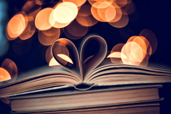 Paper book in the shape of a heart on a bokeh background. valentine's day. love symbol
