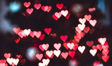 Bir düğün kartı ya da Sevgililer Günü için siyah bir zemin üzerinde pembe ve kırmızı Bokeh kalpleriyle soyut bulanıklık