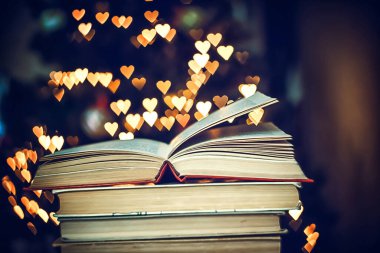 Geçmişe dönük bir yığın kitap ve arka planda Bokeh Heart ışıkları. Sevgililer Günü konsepti
