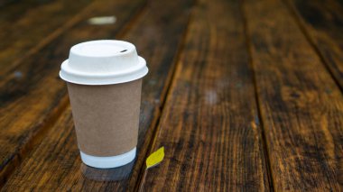 Geri dönüşümlü fincanda kahve ile yağmurlu bir gün. Dışarıdaki ahşap masada tek kullanımlık bardak. Sonbahar kahvesi.