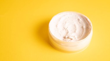 Sarı arka planda çamur maskesi. Pembe yüz maskesi kremi. Pembe kil maskeli reklam fotoğrafı. Yüz bakımı resmi