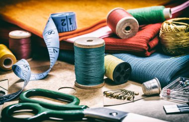Yaratıcı bir imaj. Dikiş için iplik dikmek ve dikiş işi için çeşitli aksesuarlar. Dikiş için bir takım aksesuarlar, iplik makaraları, kumaşlar, makas ve yüksük gibi yakın çekim. Retro biçimi 