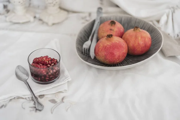 Fruchtstillleben. Granatäpfel in Obstschale und geschälte Früchte im Glas mit Wein fertig zum Essen. — Stockfoto