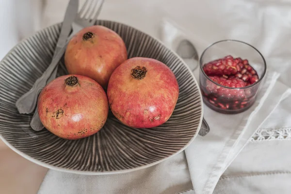 Fruchtstillleben. Granatäpfel in Obstschale und geschälte Früchte im Glas mit Wein fertig zum Essen. — Stockfoto