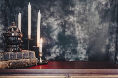 Kütüphane masasında karanlıkta yakılmış eski antika kitaplar..