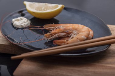 Pişmiş karidesler, taş bir levhada tüketilmek üzere sunuluyor..