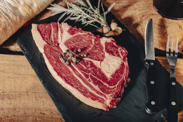 Nyers friss márványos hús steak és fűszerek a sötét márvány háttér. — Stock Fotó