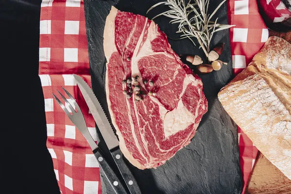 Nyers friss márványos hús steak és fűszerek a sötét márvány háttér. — Stock Fotó