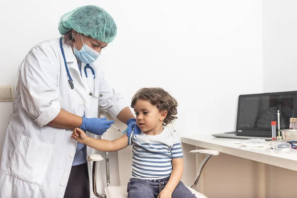 予防接種の概念。青い背景にかわいい男の子をワクチン接種女性医師、クローズアップ. — ストック写真