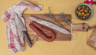 Fuets Katalan kuru sosisleri. İspanyol sosisi ve kurutulmuş et chistorra, sucuk, salçon, fuet, zeytin, biberiye ahşap zemin üzerinde kırmızı biber. en üstteki görünüm.