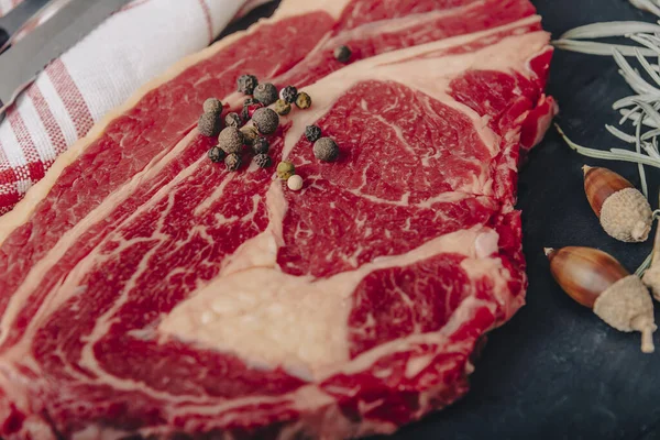 Raw beef filet mignon steak rozmaringgal, borssal és sóval sötét rusztikus lapon, fekete angus hússal. — Stock Fotó