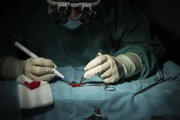 Female surgeon performs a micro-surgery operation on one arm